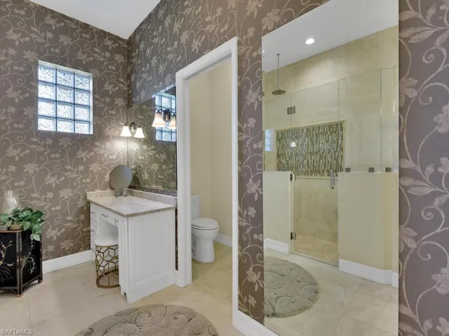 Full bath featuring a stall shower, wallpapered walls, and vanity