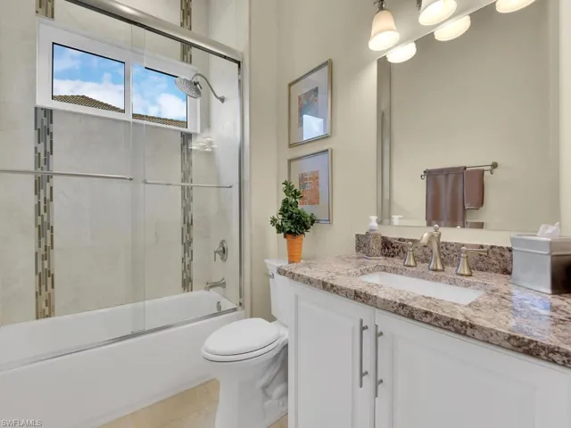 Bathroom featuring vanity, bath / shower combo with glass door, and tile patterned flooring