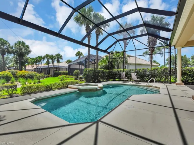 View of pool featuring a patio, a pool with connected hot tub, and glass enclosure