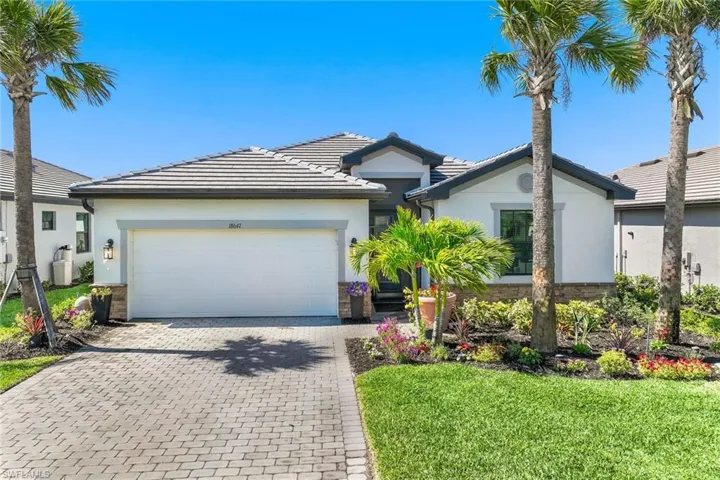 Single story home with decorative driveway, a garage, a tiled roof, a front yard, and stucco siding