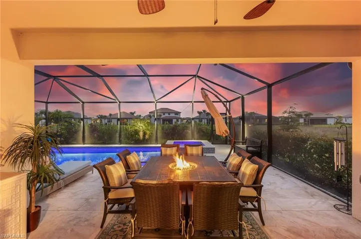 Patio terrace at dusk with a lanai, an outdoor pool, and outdoor dining space
