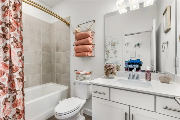 Bathroom with shower / bath combo with shower curtain, toilet, and vanity
