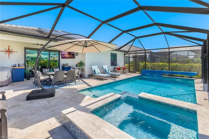 View of pool featuring a ceiling fan, outdoor dining space, a patio, a lanai, and a pool with connected hot tub