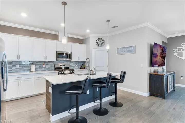 Kitchen with a sink, decorative backsplash, stainless steel appliances, light wood-style flooring, and visible vents