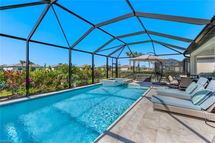 View of pool featuring a residential view, a patio area, glass enclosure, and a pool with connected hot tub