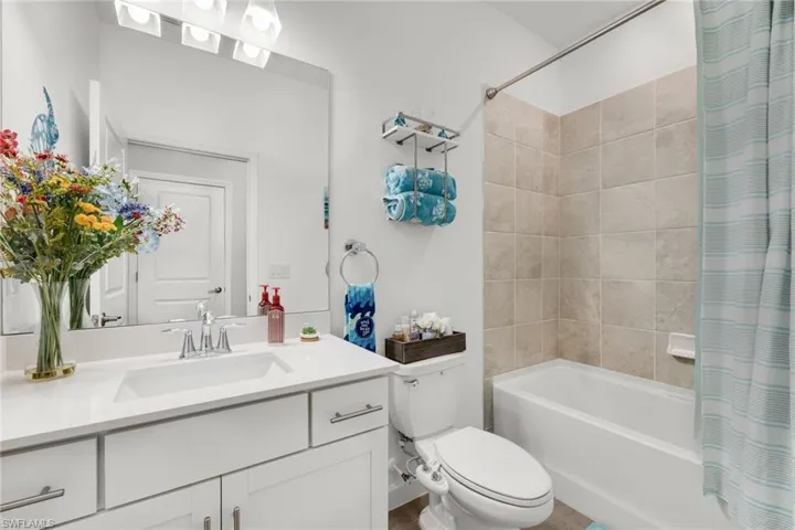 Bathroom with toilet, vanity, and shower / tub combo with curtain
