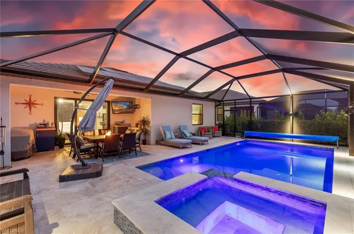 View of swimming pool featuring a covered pool, glass enclosure, outdoor dining area, an in ground hot tub, and a patio