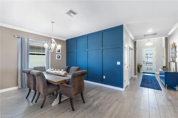 Dining room featuring a notable chandelier, crown molding, visible vents, and light wood-style flooring