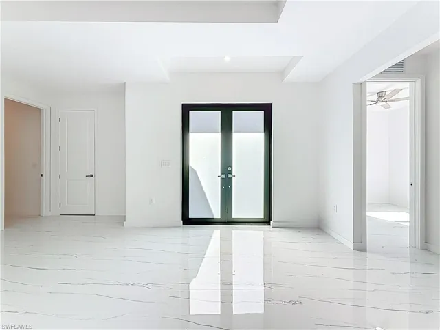 Unfurnished room featuring french doors and light marble finish flooring