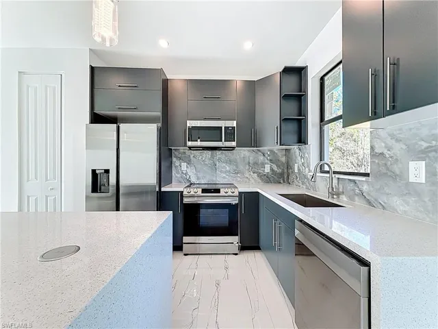 Kitchen with open shelves, light stone counters, stainless steel appliances, backsplash, and recessed lighting