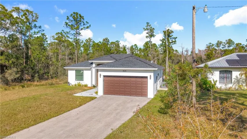 View of front of home featuring a front yard, stucco siding, concrete driveway, a shingled roof, and an attached garage