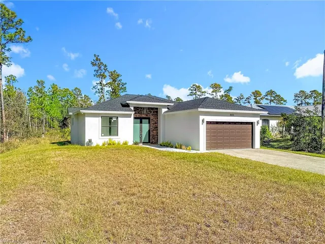 Prairie-style home with a front yard, driveway, stucco siding, stone siding, and an attached garage