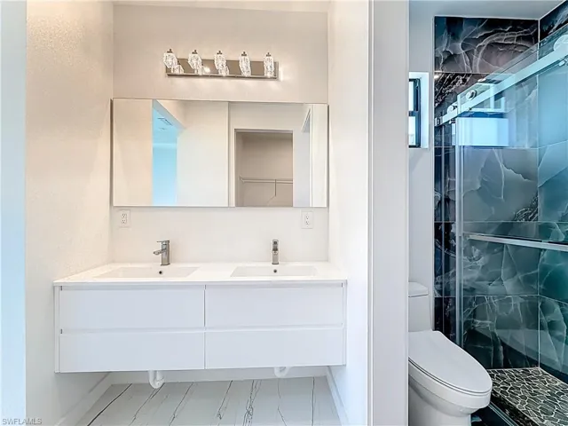 Bathroom with double vanity and a marble finish shower