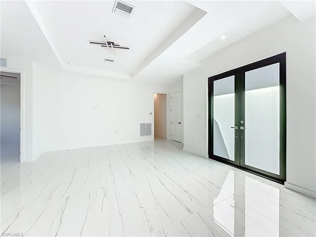Spare room featuring a raised ceiling, recessed lighting, and french doors
