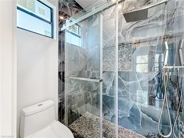Full bath with plenty of natural light and a marble finish shower