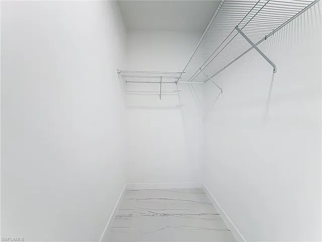 Walk in closet with light marble finish flooring