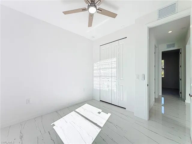 Unfurnished bedroom featuring light marble finish flooring, a closet, and a ceiling fan