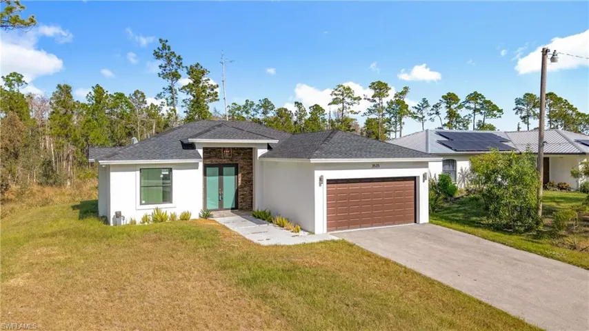 View of front of home with a front yard, stone siding, stucco siding, driveway, and an attached garage
