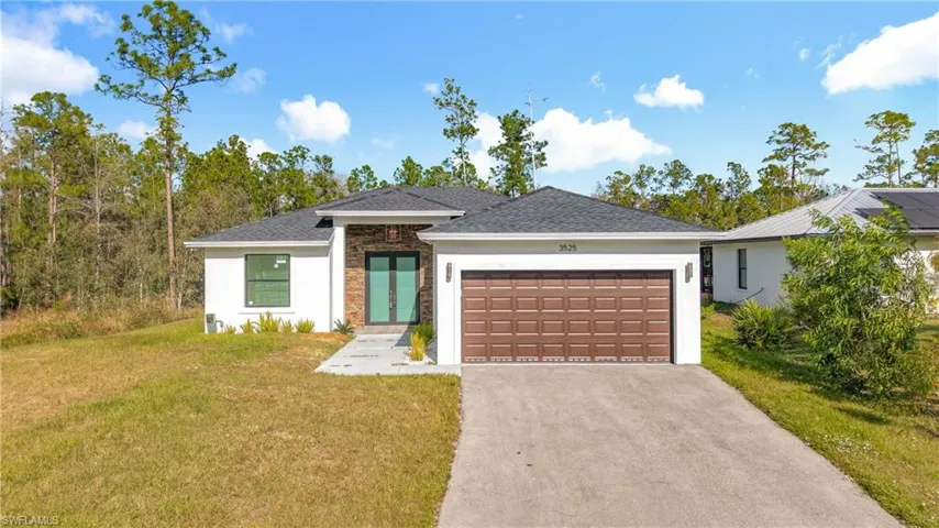 View of front of home with a front yard, asphalt driveway, stone siding, stucco siding, and an attached garage