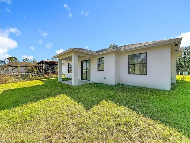 Back of house featuring a patio, a yard, and stucco siding