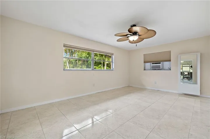 Empty room featuring cooling unit, ceiling fan, and light tile patterned floors