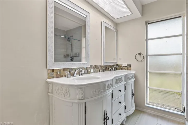 Bathroom with tile patterned floors, a healthy amount of sunlight, double sink vanity, and backsplash