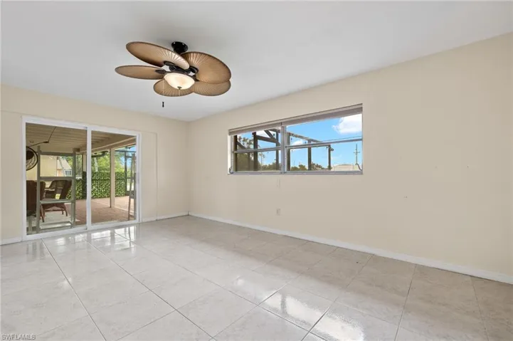 Empty room with light tile patterned flooring, ceiling fan, and a healthy amount of sunlight