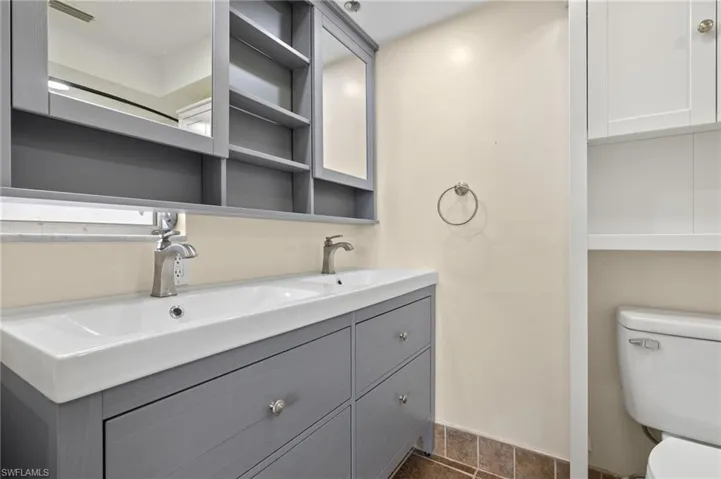 Bathroom with dual vanity, tile patterned floors, and toilet