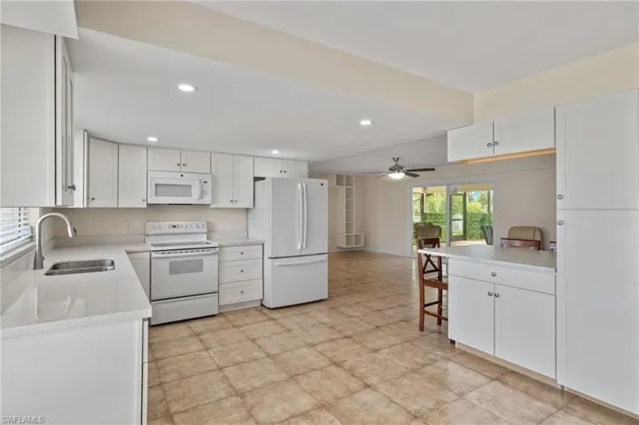 Kitchen with sink, light tile patterned flooring, ceiling fan, and white appliances