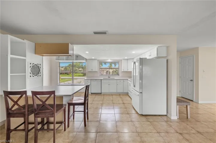 Kitchen featuring sink, white appliances, light tile patterned floors, and white cabinets