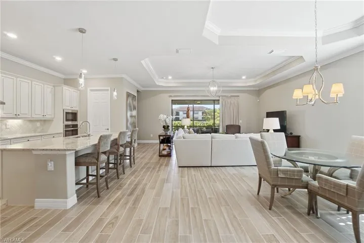 Dining room with ornamental molding, a chandelier, wood finish floors, recessed lighting, and a raised ceiling