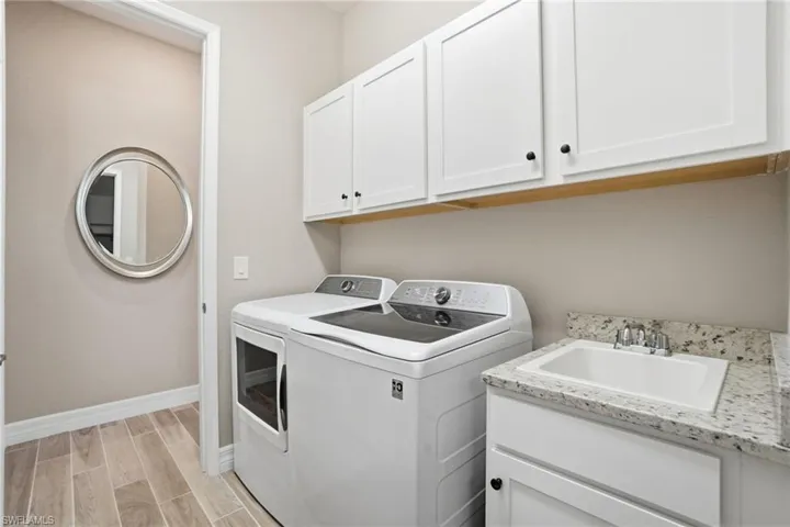 Laundry room featuring wood tiled floors, washing machine and clothes dryer, and cabinet space
