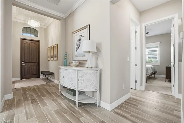 Foyer featuring wood finish floors, a chandelier, and crown molding