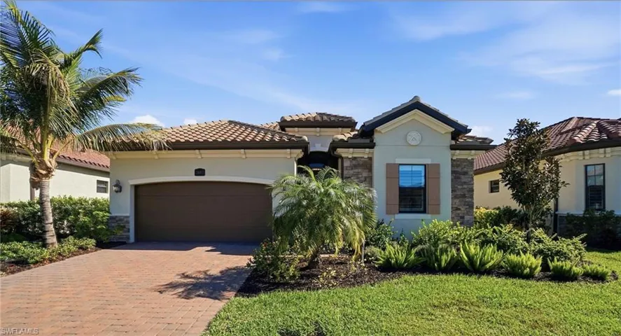 Mediterranean / spanish home with decorative driveway, stucco siding, an attached garage, stone siding, and a tiled roof