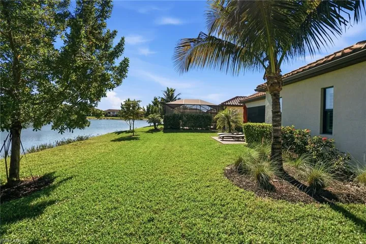 View of grassy yard featuring a water view, glass enclosure, and a patio