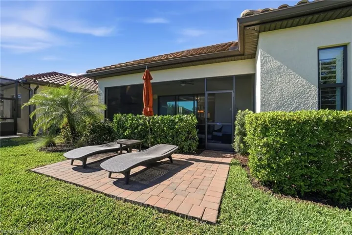 Rear view of house featuring stucco siding, a patio, a tiled roof, a sunroom, and a yard