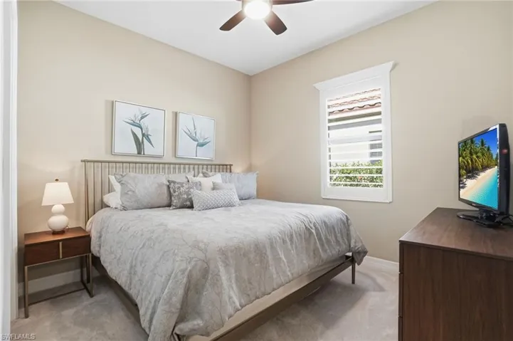 Bedroom with a ceiling fan and light colored carpet