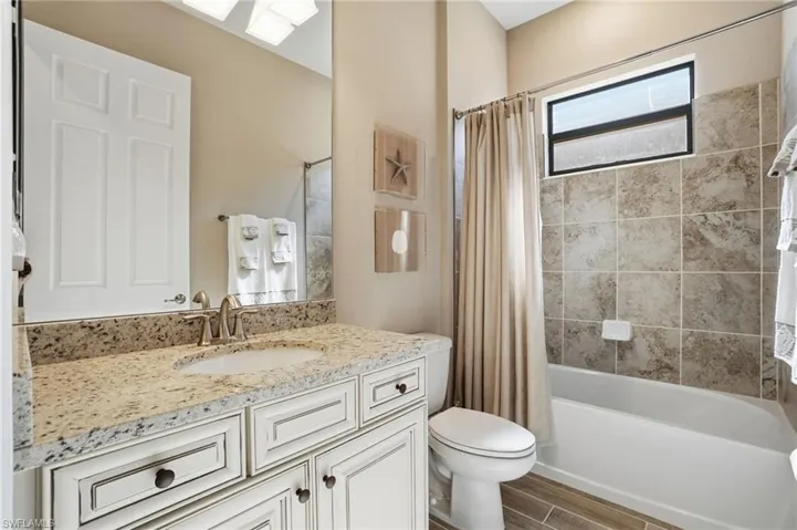 Bathroom with vanity, shower / bath combination with curtain, and wood tiled floors