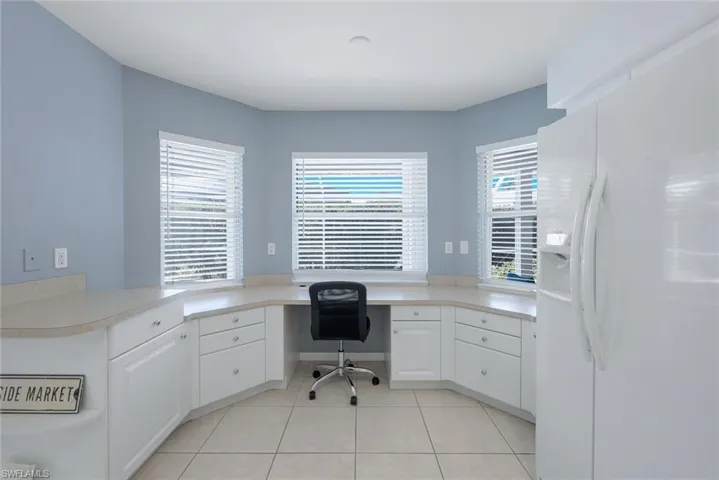 Office area featuring built in desk and light tile patterned floors