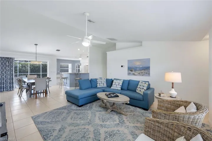 Living room featuring light tile patterned flooring, ceiling fan, and vaulted ceiling