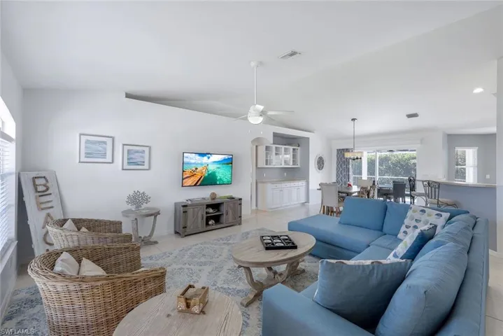 Living room with ceiling fan, lofted ceiling, and light tile patterned floors