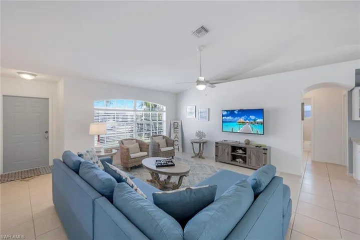 Tiled living room featuring vaulted ceiling and ceiling fan