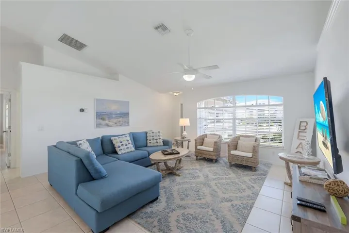 Living room featuring light tile patterned floors, vaulted ceiling, and ceiling fan