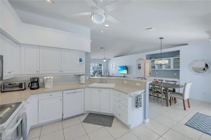 Kitchen with white cabinetry, white appliances, kitchen peninsula, and sink