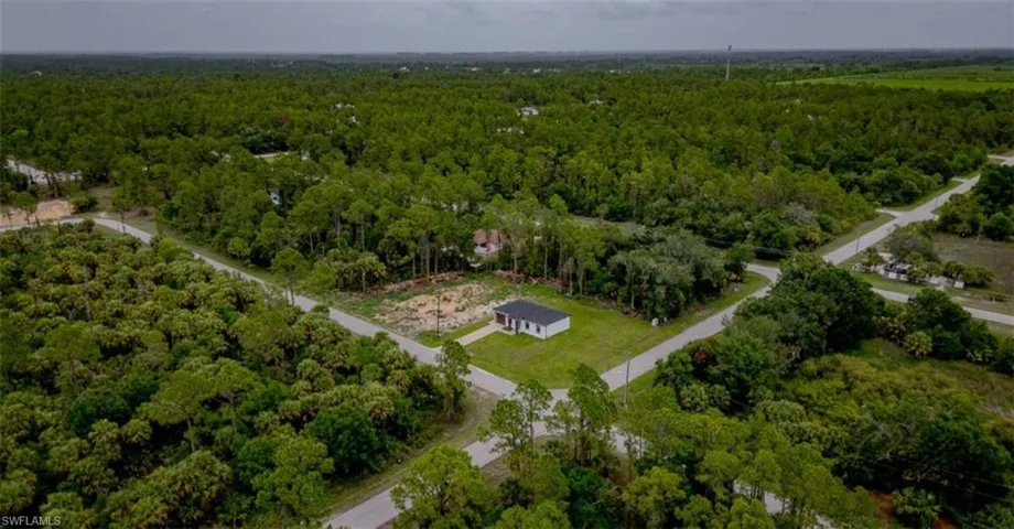 Aerial view of property and surrounding area with a forest
