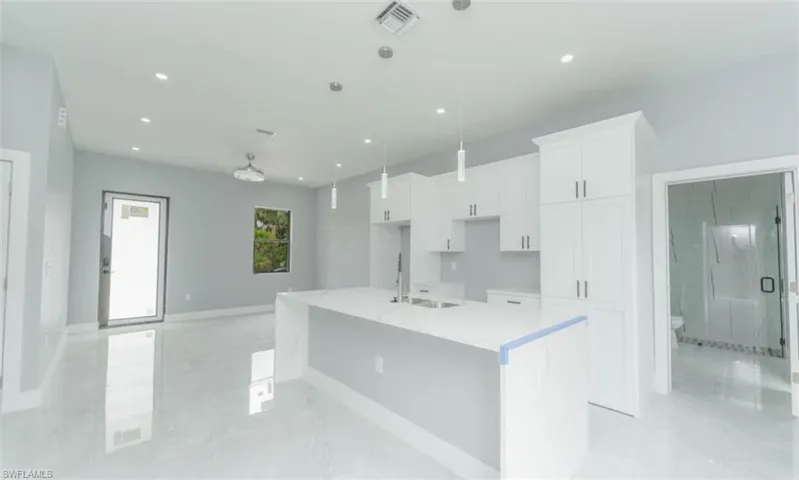 Kitchen with white cabinetry, a center island with sink, recessed lighting, and pendant lighting