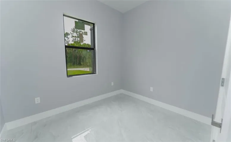 Spare room with marble look tile flooring and baseboards