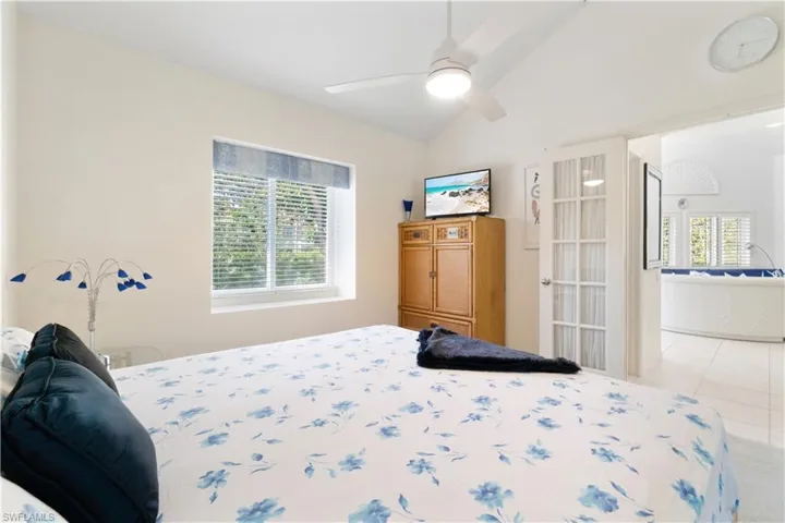 Tiled bedroom with ceiling fan, lofted ceiling, and multiple windows