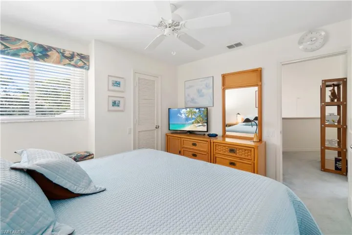 Bedroom featuring ceiling fan, light carpet, and a closet