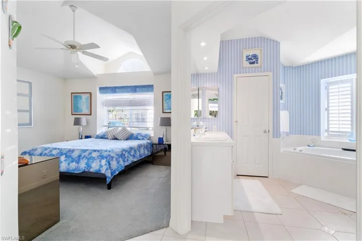 Bedroom with ceiling fan, sink, light colored carpet, and lofted ceiling